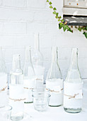 Clear glass bottles wrapped in torn fabric