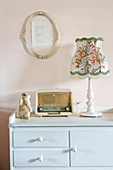 Old-fashioned table lamp and old radio on pale blue cabinet
