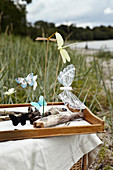 Gebastelte Schmetterlinge und Libellen an Treibholz in einem Tablett