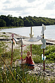 The child sits under a canopy with butterfly decorations on the beach doing crafts