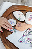 Kinderhand bastelt mit Steinen, Aufklebern und Schmetterling-Motiven