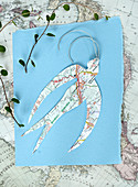 Swallow cut out of map on blue paper