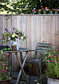 Rustikaler Sitzplatz auf der Terrasse mit Bretterwand und Sommerblumen