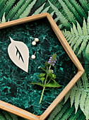 Fünfeckiges Tablett mit Klebefolie wie grüner Marmor auf Papier mit Farnblatt-Motiv