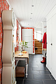 Long stretch of a hallway with an antique grandfather clock and black floor tiles in restored mission style house