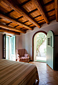 Mediterranes Schlafzimmer mit Terrakottafliesenboden und Tür zum Garten