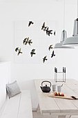 Wall decoration with a bird motif above the light wooden table