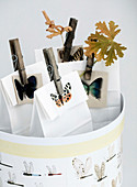 Papiertüten mit Schmetterlingmotiven und Holzklammern in runder Schachtel