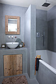 Rustikales Bad in Grau mit eingebauter Wanne und Waschtisch mit Holztür
