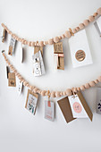 Wooden beaded Garland with postcards hanging on a white wall