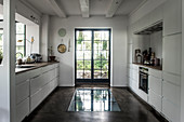 Weiße Einbauschränke vor Fenster und Boden mit Glaseinsatz vor Fenstertür in der Küche