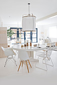Runder Tisch mit Klassikerstühlen in weißem, offenem Wohnraum