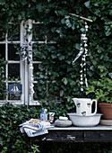 Rustikale Waschstation auf altem Tisch am Gartenhaus mit Efeu