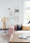 Pink upholstered suite, golden table lamp, and rustic coffee table in the living room