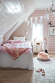 A bed in a girl's room decorated in pink and white