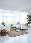 White sofas and a round table in front of a window in an open-plan living room