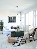 A vintage wooden chest as a coffee table and a armchair on a diamond-patterned rug in a living room