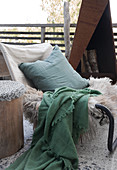 Cushions, animal fur and a plaid on a chair on a terrace