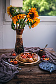 Aprikosen-Galette vor Sonnenblumenstrauß auf rustikalem Holztisch