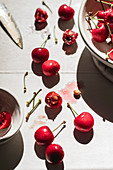 Frische Kirschen in Schale und verteilt auf Tisch, teilweise aufgebrochen