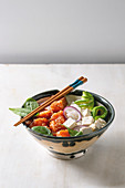 Poke bowl with soy sauce marinated salmon, rice, avocado and tofu cheese served in ceramic bowl with chopsticks