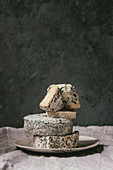 Variety of french blue cheese in stack on plate with flowing honey on grey linen table cloth