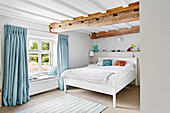 Bright and contemporary bedroom with painted beams and blue accents