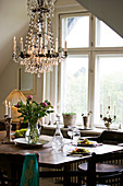 The chandelier above a classic, wooden table