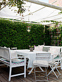A sheltered seating area on a covered terrace with white furniture