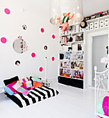 reading nook in front of the wall with pink dots and the shelf in the nursery