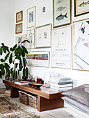 Wooden bench with books and small bowls and indoor plant in the living room with a collection of pictures and illustrations