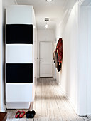 Black and white cupboard in the hallway with light wooden floorboards
