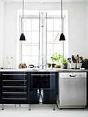 Black high-gloss kitchen with stainless steel worktop in front of the window in an old building