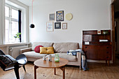 An antique bureau, a sand-coloured sofa, a coffee table and a designer chair in a living room
