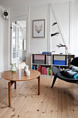 A coffee table, a black designer chair and a half-high shelf in a living room