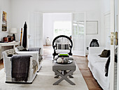 White slip covered furniture, upholstered stools as a coffee table and rattan chair in the living room