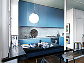 Black dining table in a modern open kitchen with blue fronts