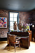 Piano with Asian statues in the room, framed poster with Queen Elizabeth on a brick wall