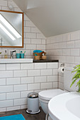 Toilet in a bathroom with white subway tiles in the attic