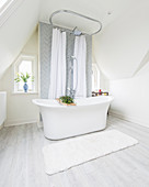 Free-standing bathtub in elegant attic bathroom with sloping walls