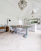 Hefty dining table and classic chairs in front of kitchen area in converted barn