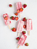 From above delicious refreshing pink freeze pops and bunch of fresh strawberries on white background