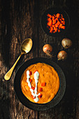 From above tasty fragrant vegetable cream soup with cut ripe carrot and onions on wooden background