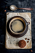 Tasse Kaffee und ein Kaffeemuffin auf alten Buchseiten