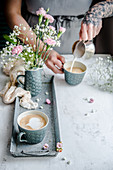 A woman pouring milk foam into a cup of coffee