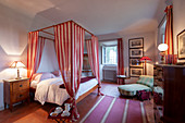 Doppelbett mit rot-weißem Vorhang, antik Kommode und Tagesbett im Schlafzimmer