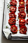 Roasted cherry tomatoes with thyme, pepper and sea salt on a baking tray