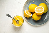 Lemon Curd, daneben Teller mit frischen Zitronen