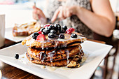 A stack of pancakes with berries on a serving platter