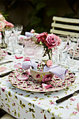 Gedeckter Tisch im Freien mit Rosenblütendeko